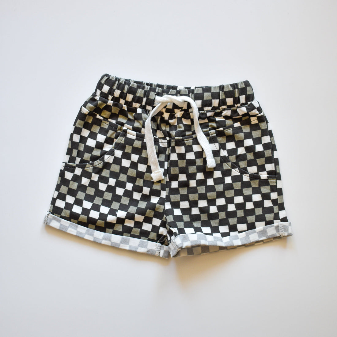 Close-up of black, grey, and white checkered 'Check Ya Later' shorts with drawstring.