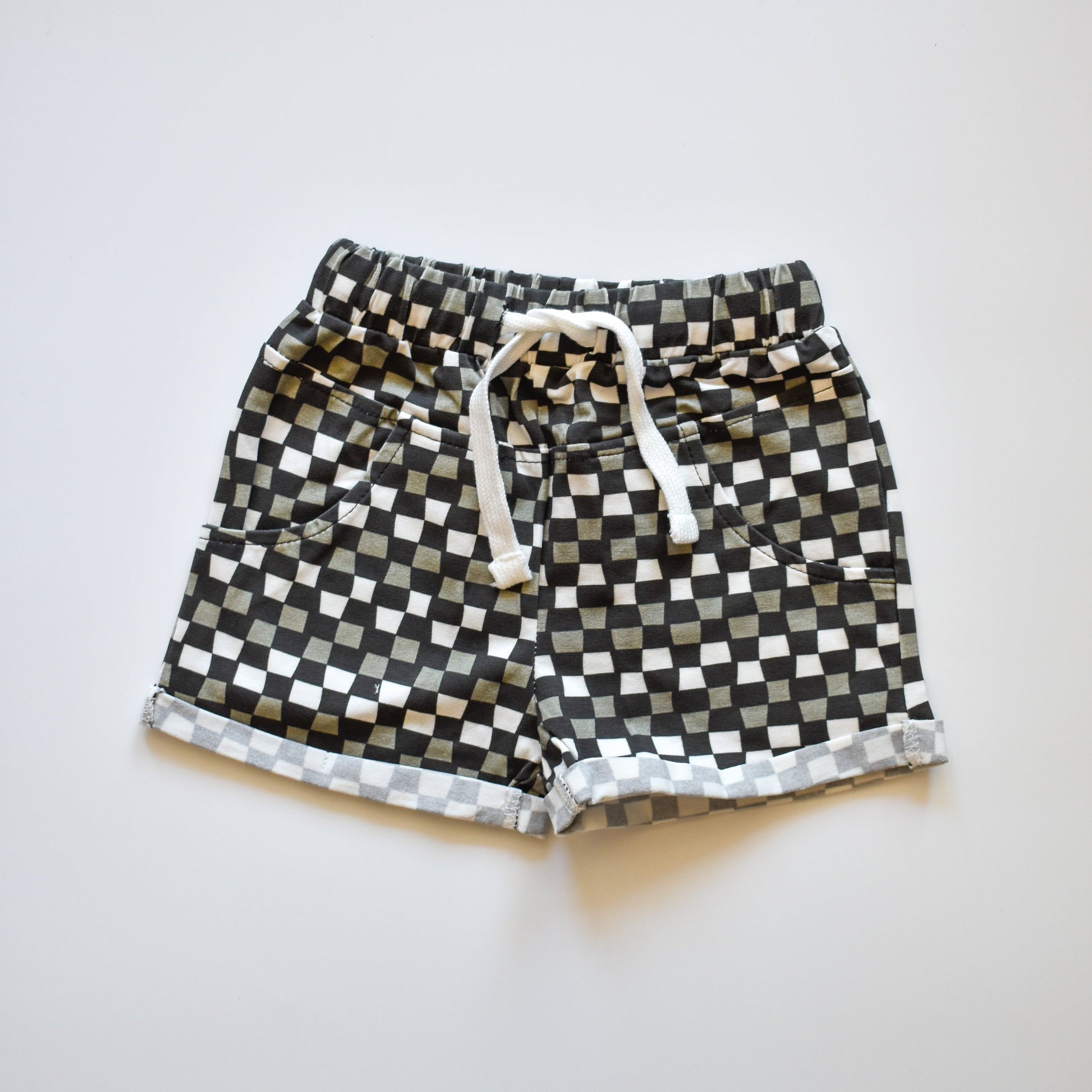 Close-up of black, grey, and white checkered 'Check Ya Later' shorts with drawstring.