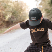 Boy wearing Juniper Green Explorer Snapback Hat and 'The Aces' t-shirt.