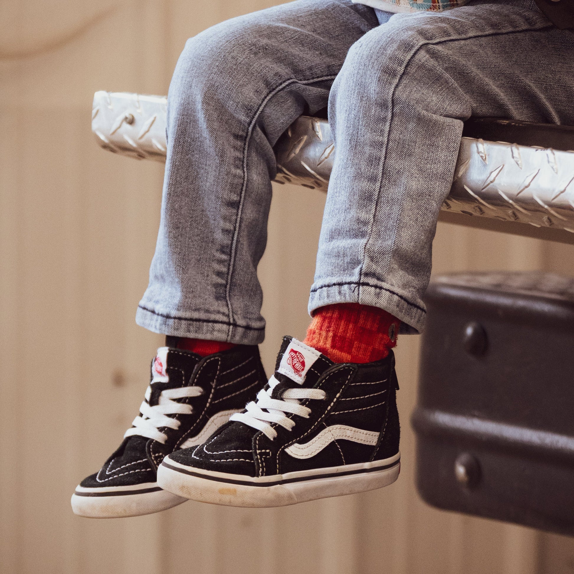 Child wearing Retrograde red/orange checkered socks with white sneakers.
