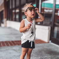 Toddler boy with lollipop wears greige Spark Muscle Tank