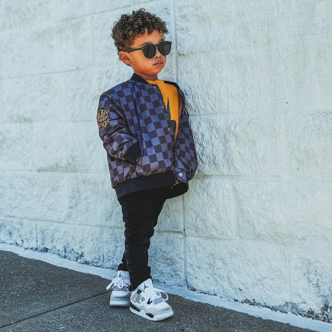 Toddler in Ocean Cubs Wear checkered letterman jacket with sunglasses