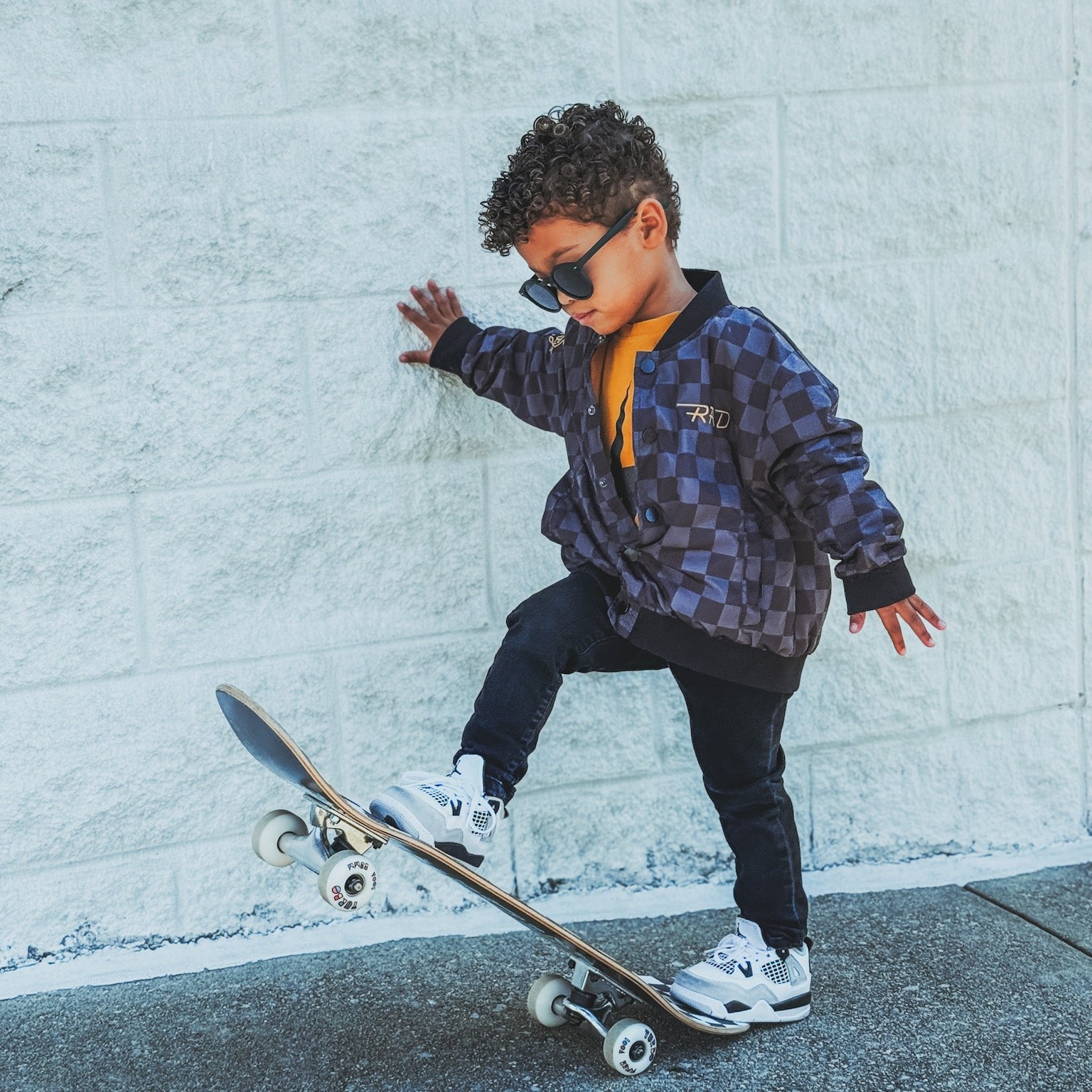 Boy in checkered waterproof jacket on skateboard