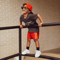 Boy wearing red/orange Retro-Wave hybrid board shorts with a hat and sunglasses.
