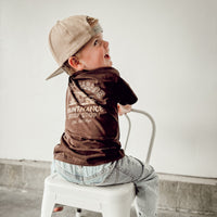 Little boy wearing brown Dudes Garage tee with vintage car design.
