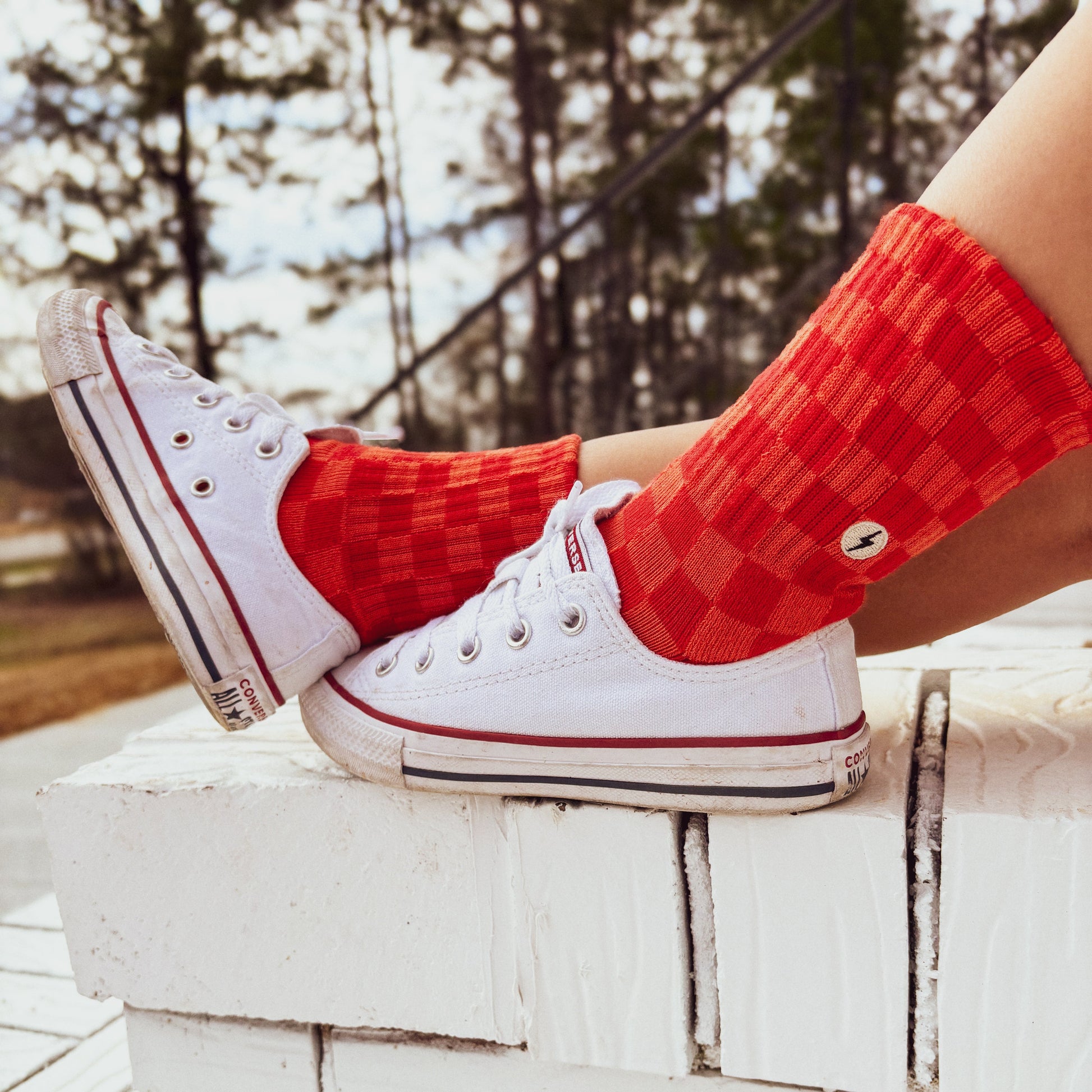 Child wearing Retrograde red/orange checkered socks with white sneakers.