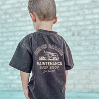 Dudes Garage vintage brown tee featuring surf shop graphic on boy outdoors.