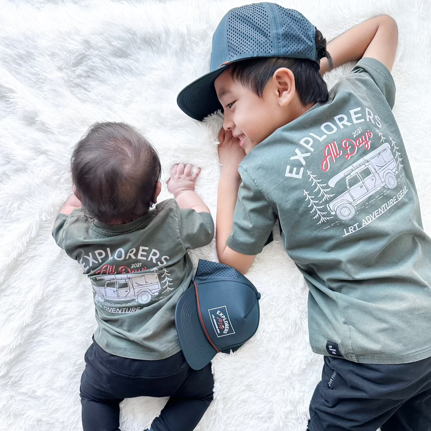 Baby and child wearing matching sage Explorer tees.