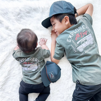 Baby and child wearing matching sage Explorer tees.
