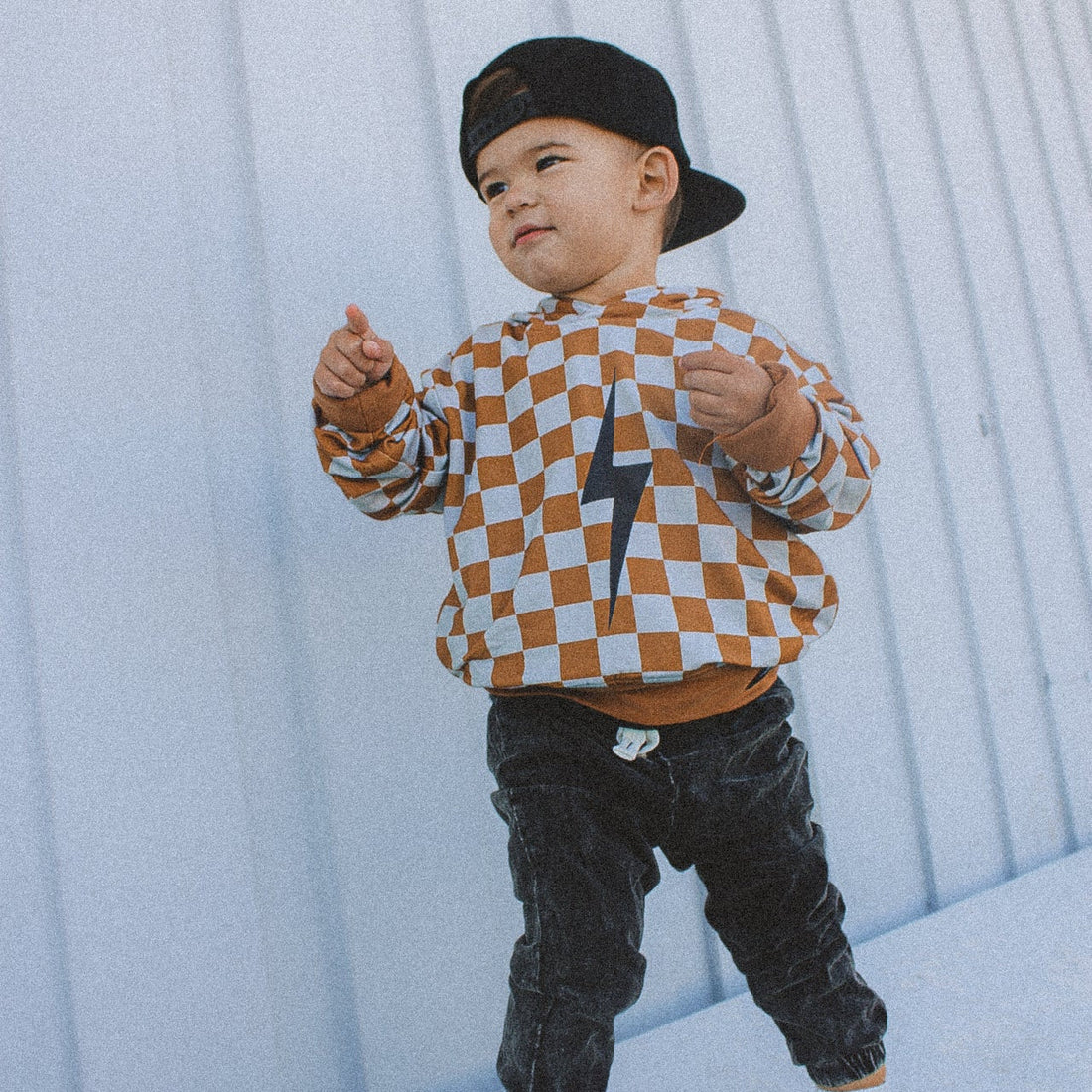 Toddler wearing rust checkered spark hoodie with black lightning bolt.