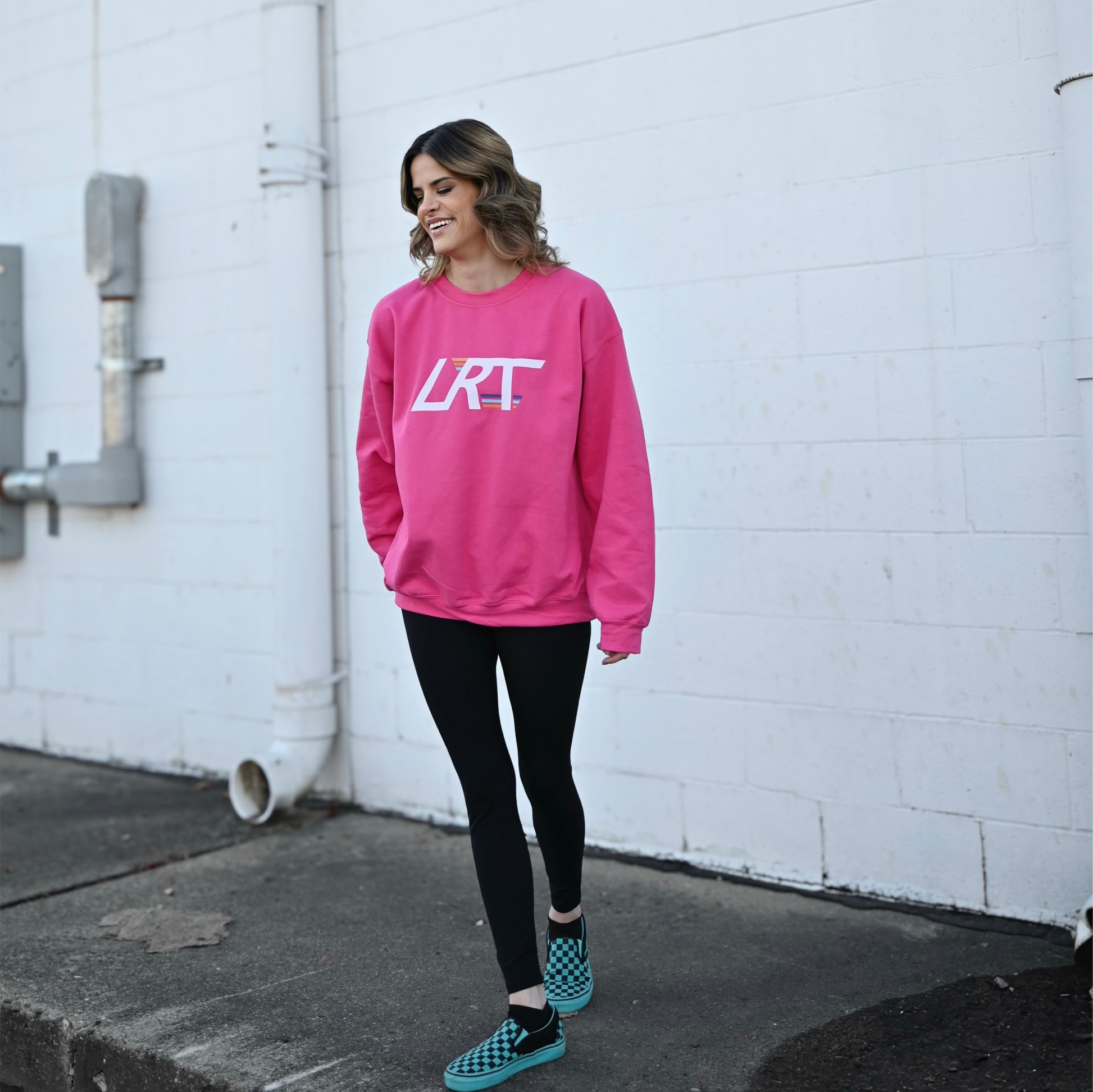 Pink LRT Winged Logo Crew Sweatshirt with leggings and checkered shoes.