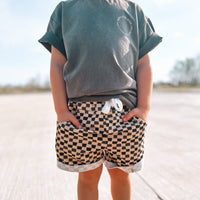 Toddler boy wearing Check Ya Later Shorts with hands in pockets.