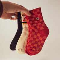 Child wearing Retrograde red/orange checkered socks with white sneakers.