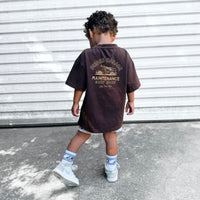 Dudes Garage vintage brown tee featuring surf shop graphic on boy outdoors.