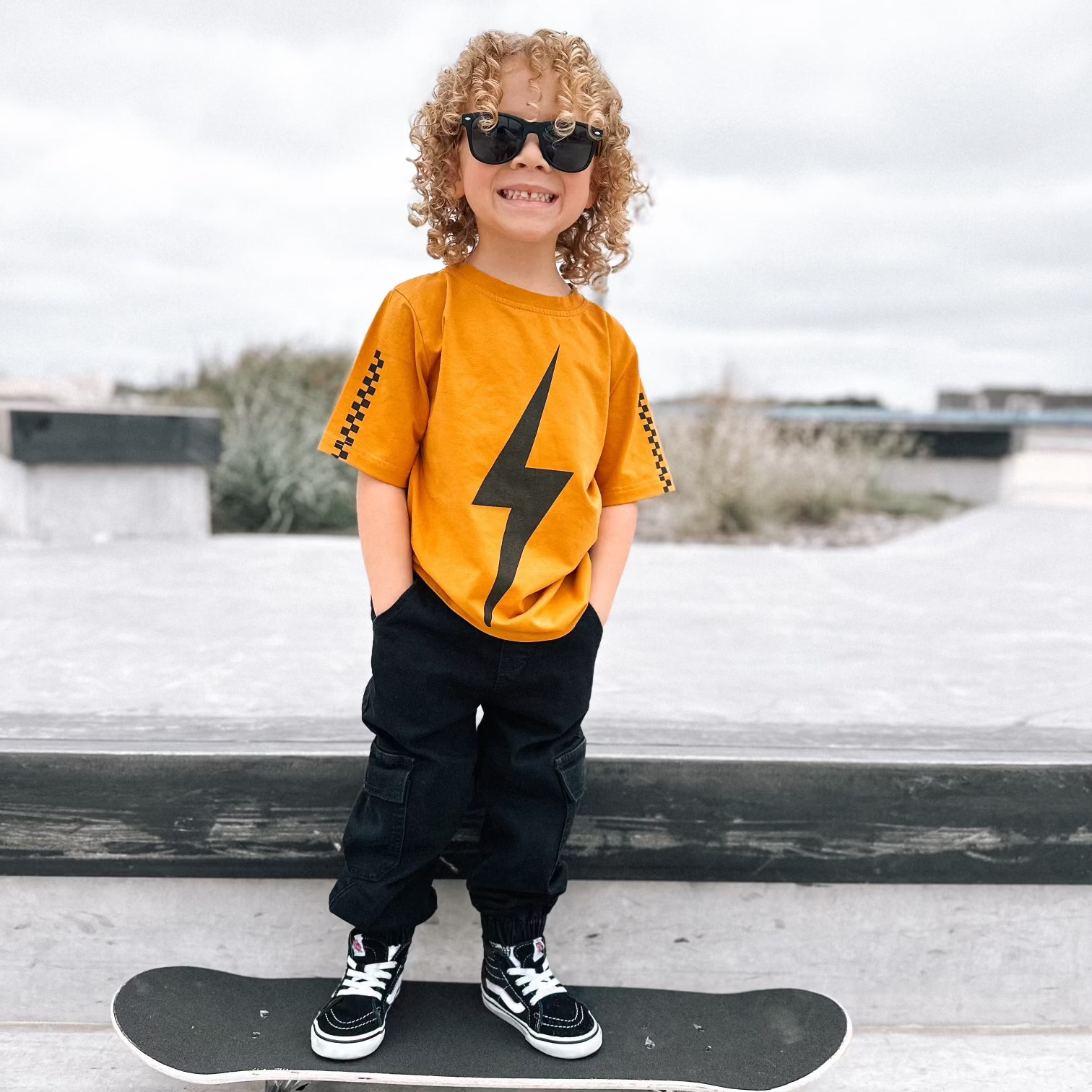 Boy in Pumpkin Spark Tee with Skateboard: A retro-inspired look for active kids.