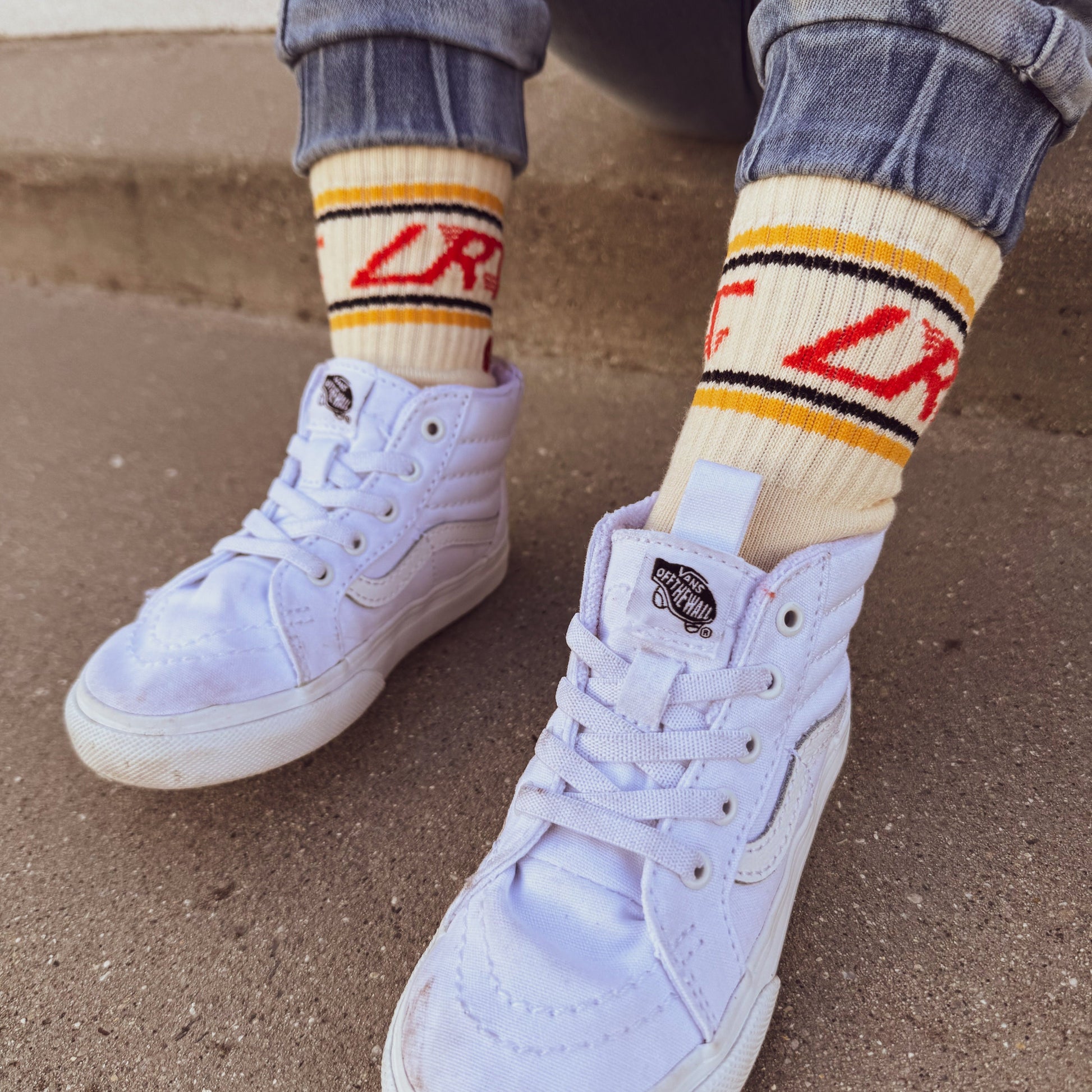 Child wearing Retrograde red/orange checkered socks with white sneakers.