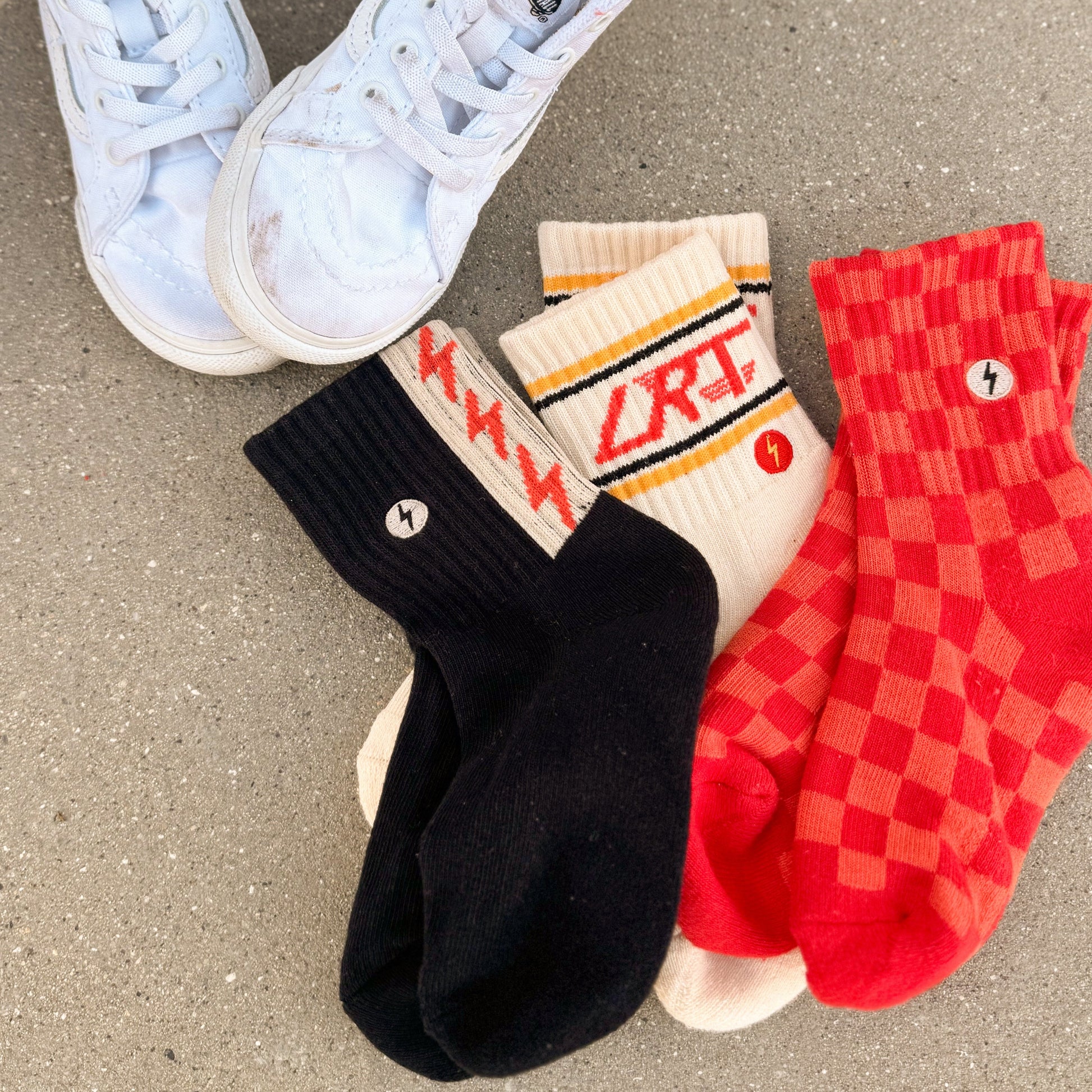 Child wearing Retrograde red/orange checkered socks with white sneakers.