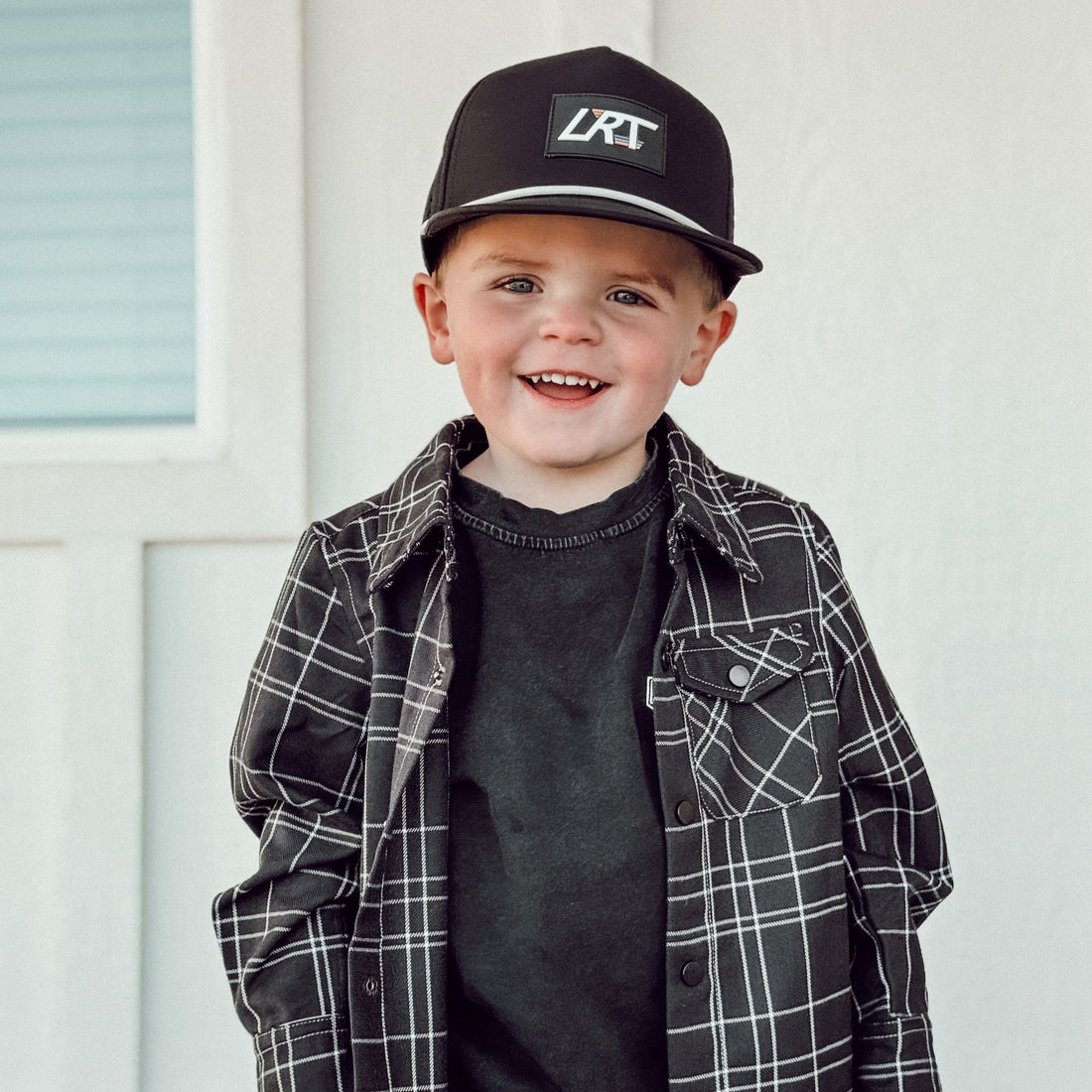 Smiling boy in black and white plaid Kids Flip Side Flannel with snap closures.