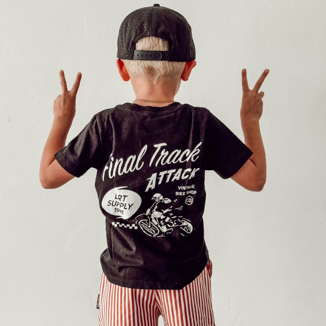 Boy wearing black Final Track Attack Tee with peace signs.