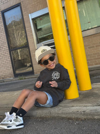 Boy in grey Radiator Hoodie leaning against a pillar.