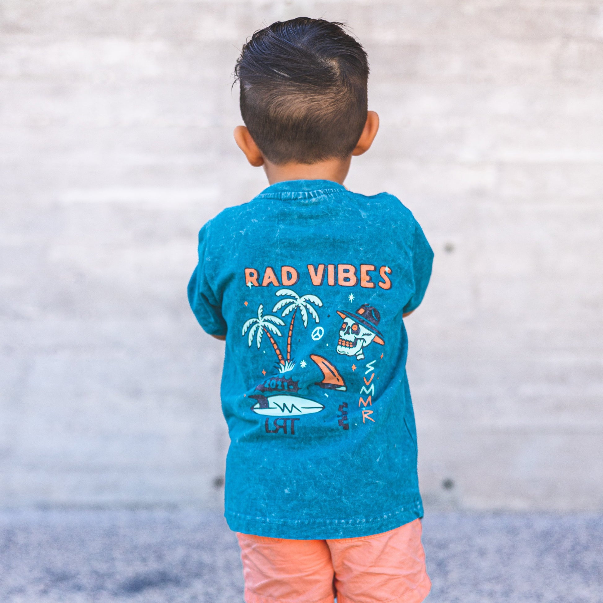 Boy in 'Rad Vibes' graphic tee with arms crossed