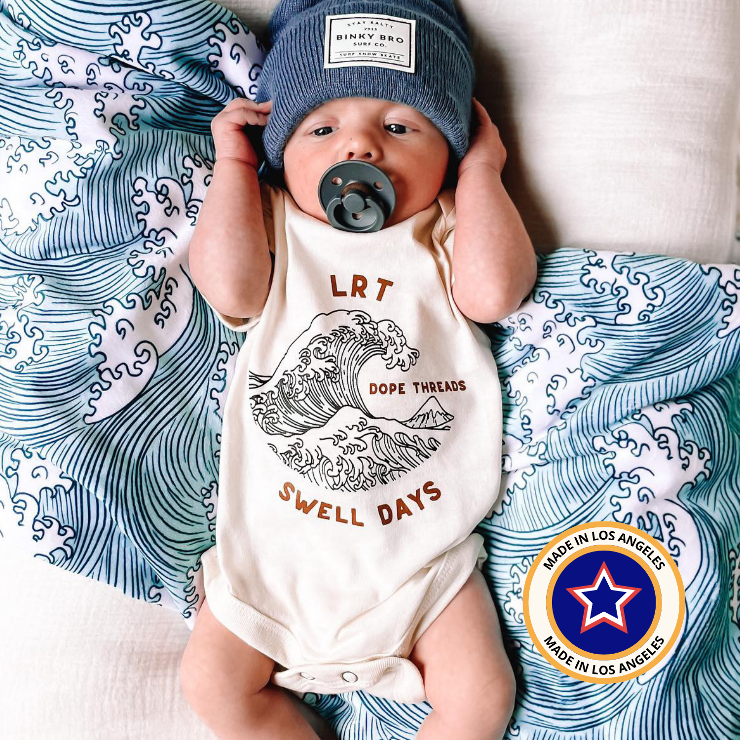 Baby wearing Dope Threads Swell Days onesie with 'Made in Los Angeles' badge.