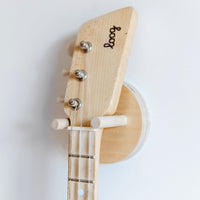 Loog guitar neck secured on a natural birch wood wall mount.