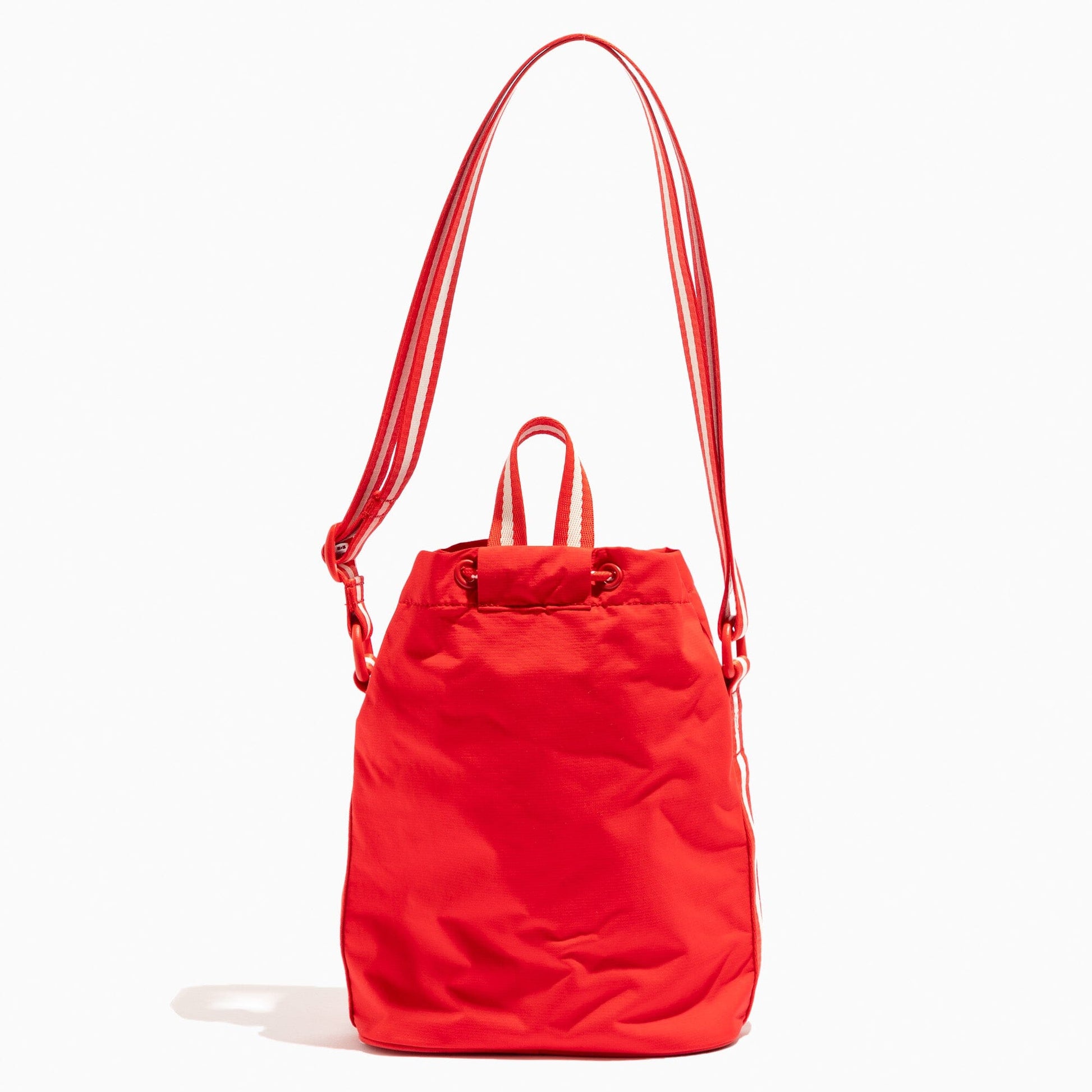 The back of the Cherry Motion Bucket Crossbody bag in red with white striped strap.