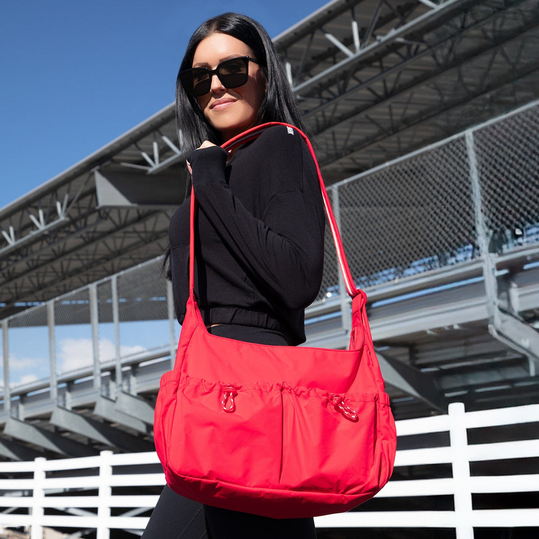 Woman wearing Cherry Motion Carryall Tote, a red nylon shoulder bag.