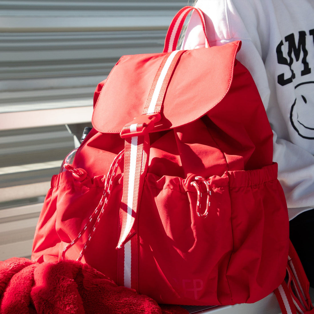 Red Cherry Motion Backpack with drawcord, worn outdoors.