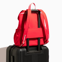 Cherry Motion Drawcord Backpack in red, attached to luggage.