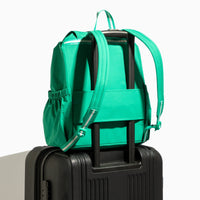 Kelly Motion green backpack attached to suitcase.