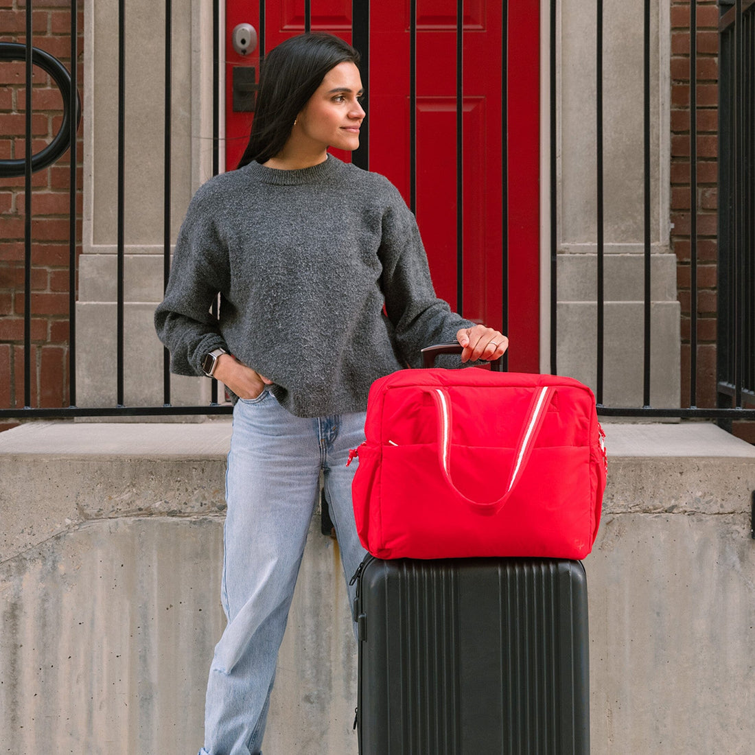 Woman with Cherry Motion Overnight Duffle in red on a suitcase.