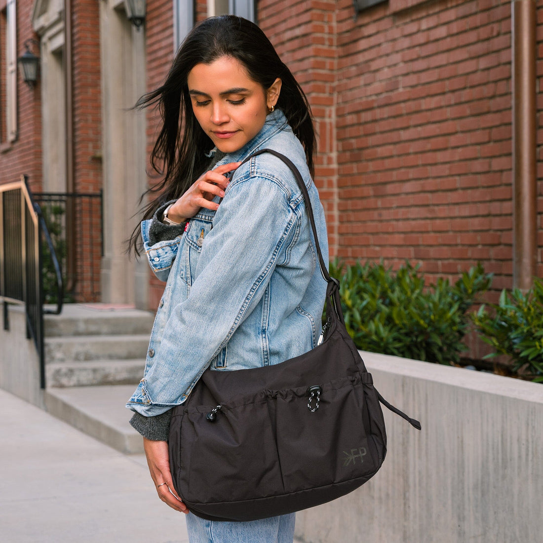 Woman wearing the black Jet Motion Carryall Tote over her shoulder.