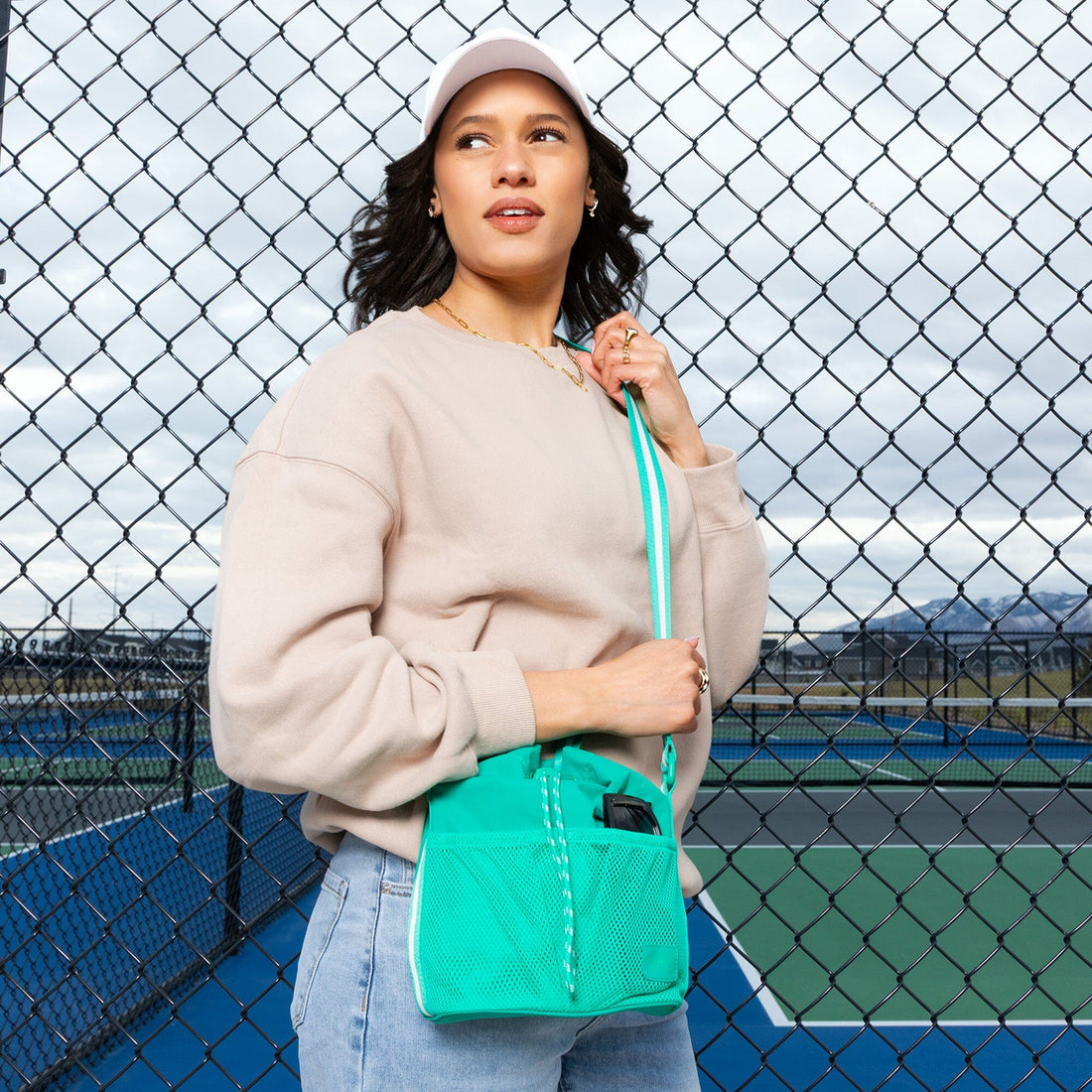 Woman wearing the Kelly Motion Bucket Crossbody bag in green.