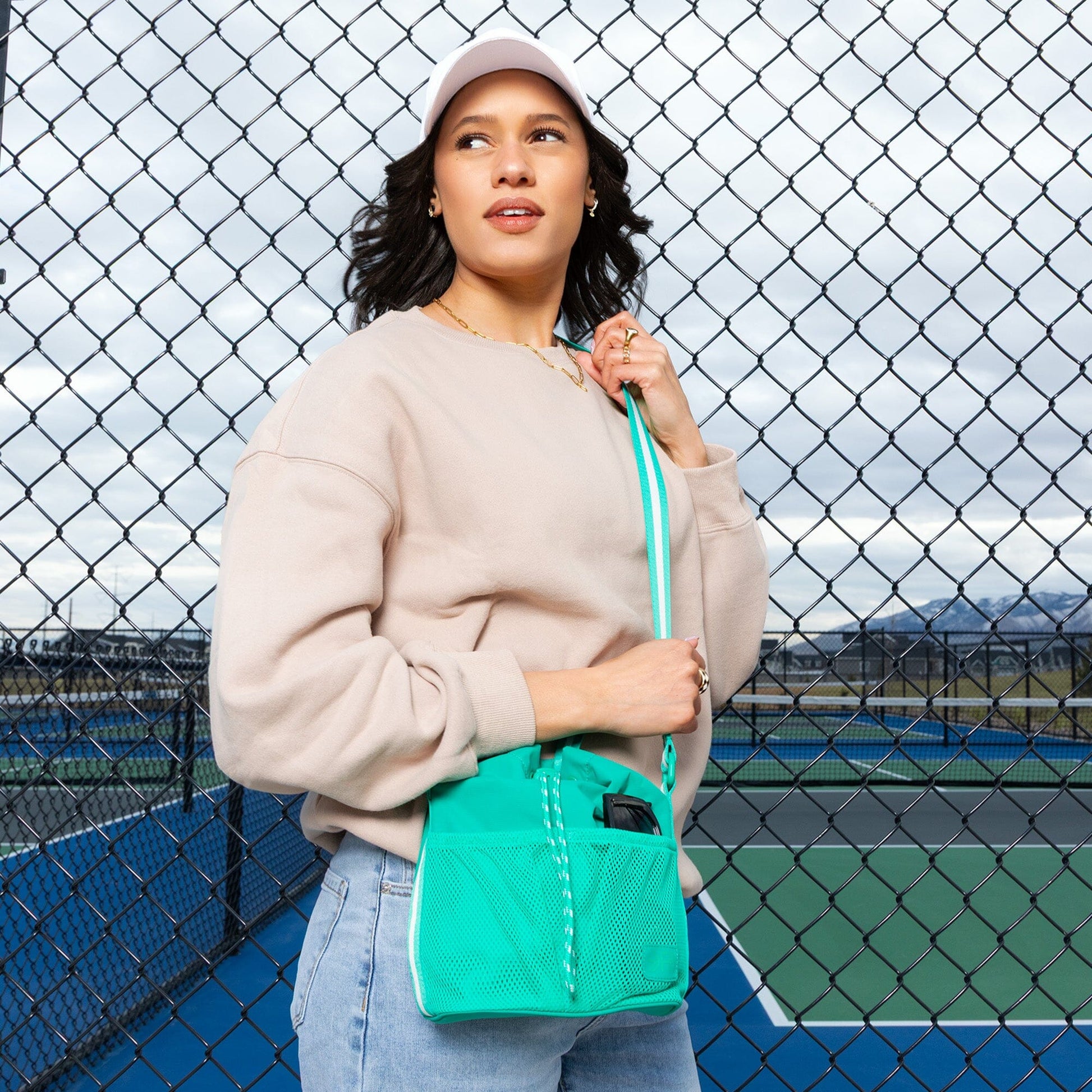 Woman wearing the Kelly Motion Bucket Crossbody bag in green.
