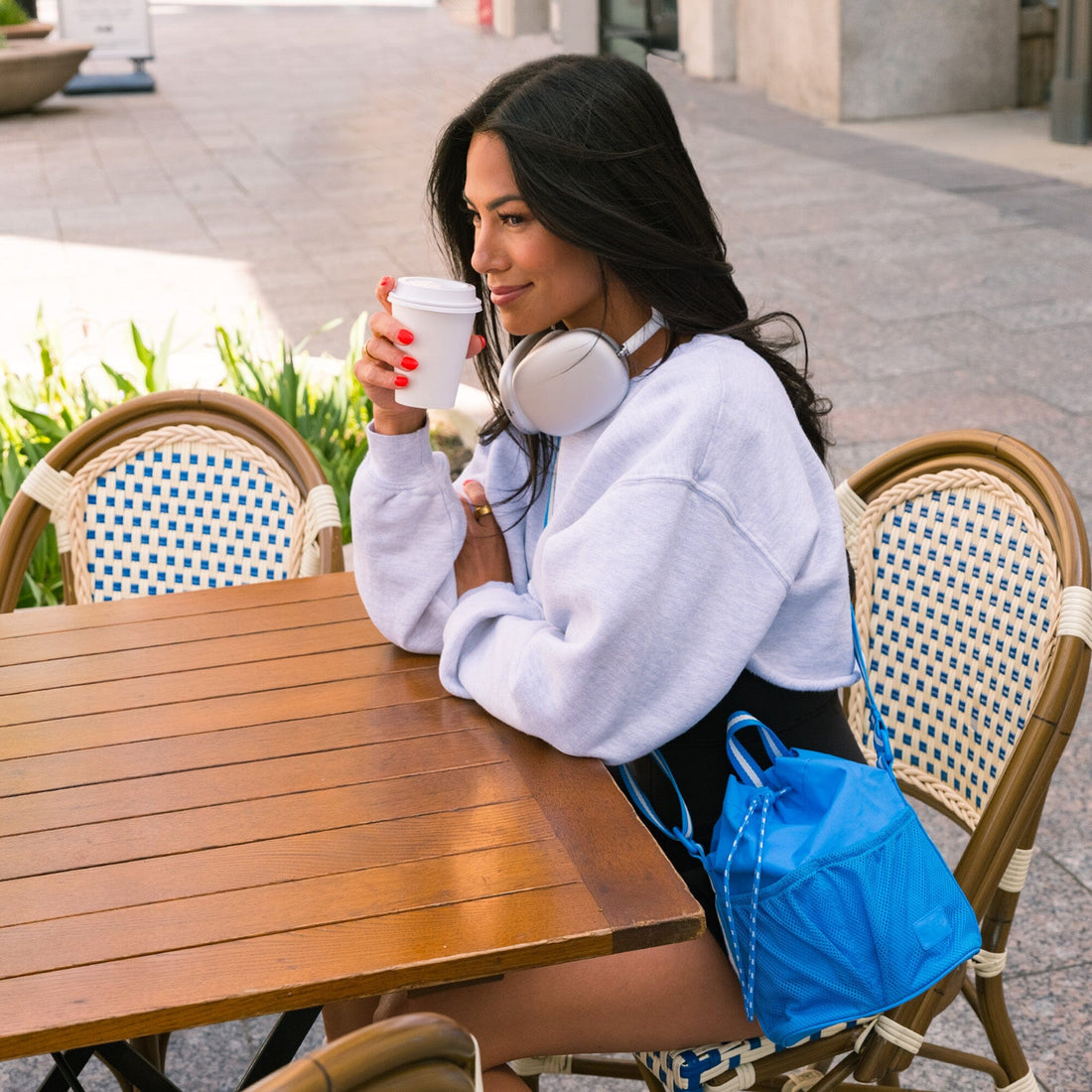 Woman at a cafe with the blue Wave Motion Bucket Crossbody bag.