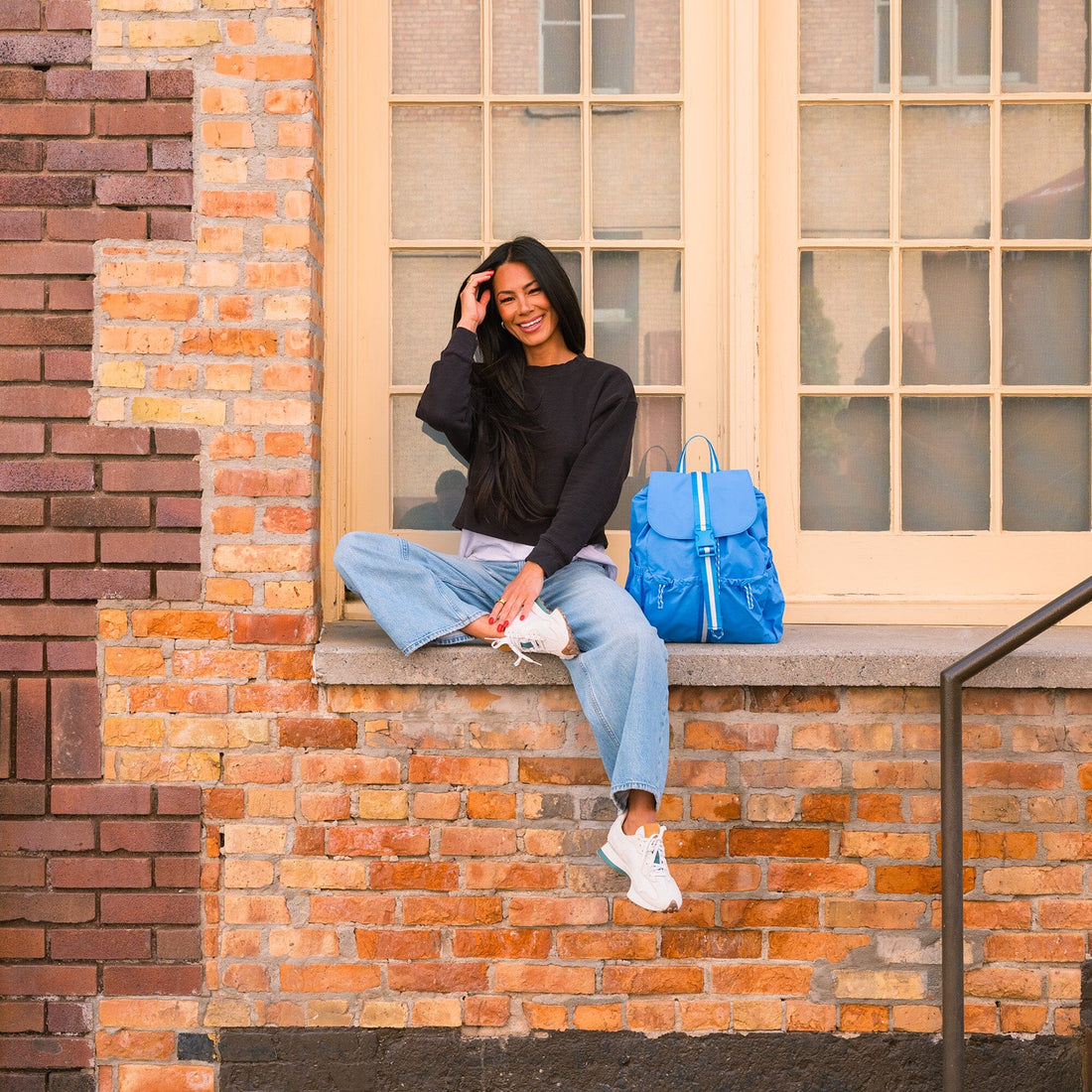 Lifestyle shot of a woman with the blue Wave Motion Drawcord Backpack.