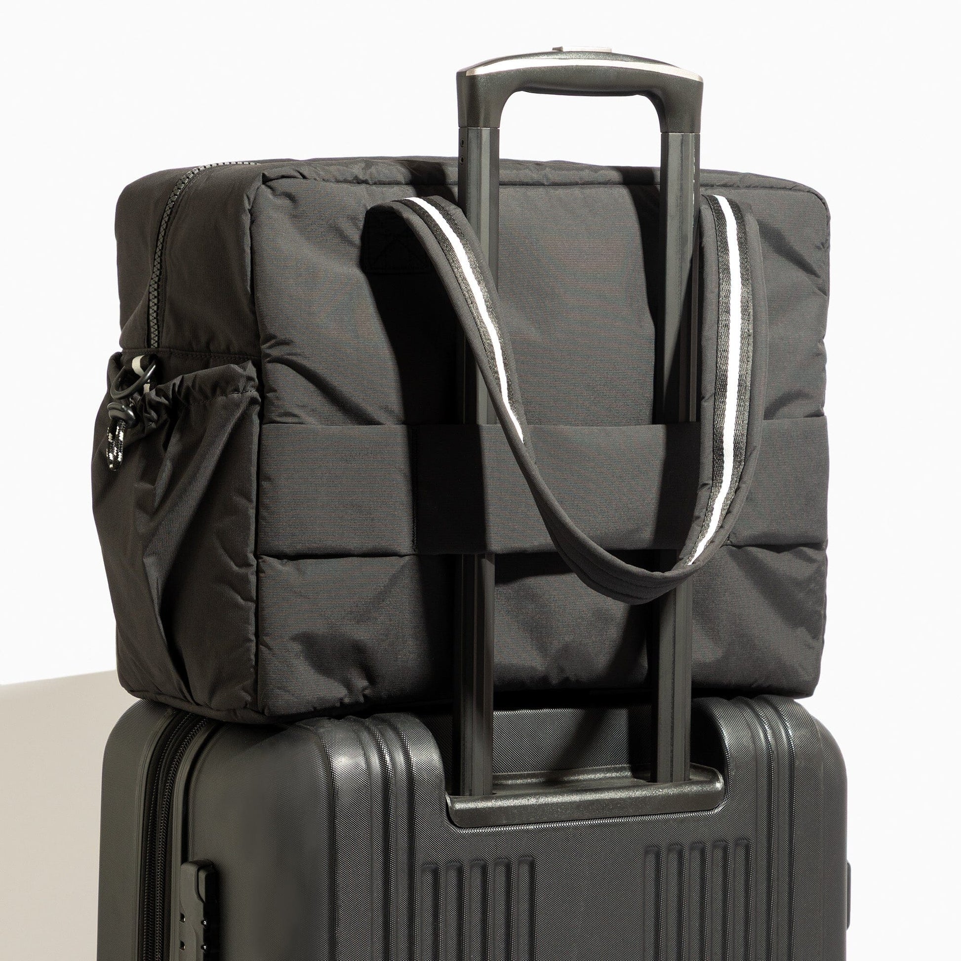 Jet Motion Overnight Duffle in black with top handles and shoulder strap, 'NEW!' badge.