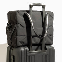 Jet Motion Overnight Duffle in black with top handles and shoulder strap, 'NEW!' badge.
