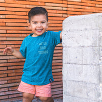 Smiling boy in 'Little Rad Things' tee and peach shorts