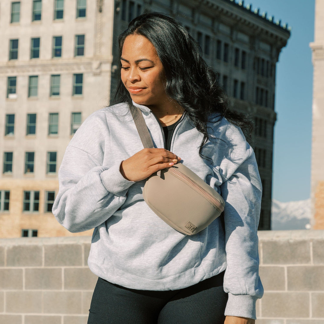 Woman wearing the Aspen Seoul Neoprene Play Pack crossbody in an urban setting.