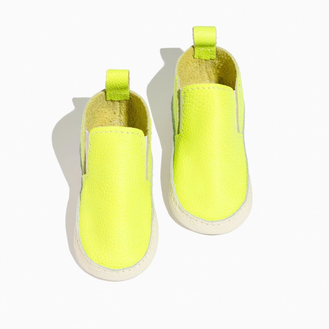 Pair of extra yellow leather slip-on baby shoes, top-down view.