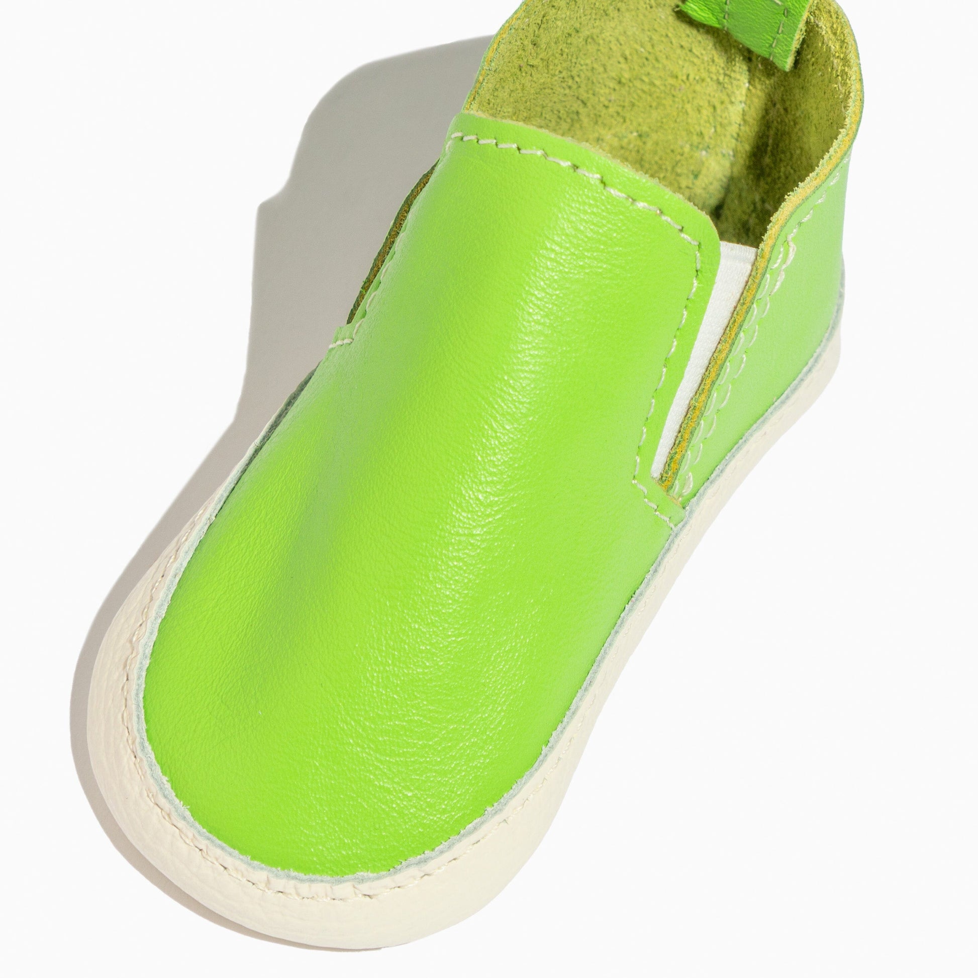 Close-up of a lime green leather baby slip-on shoe.