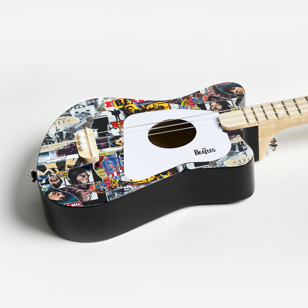Angled view of The Beatles Loog Mini Guitar showing body detail and wooden neck.
