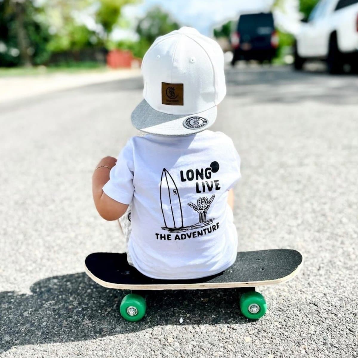 Boy on skateboard wearing white Long Live The Adventure graphic tee.