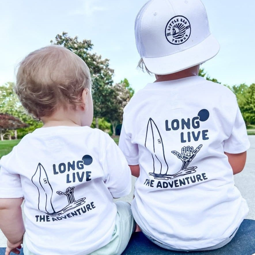 Two kids wearing Long Live The Adventure white graphic tees.