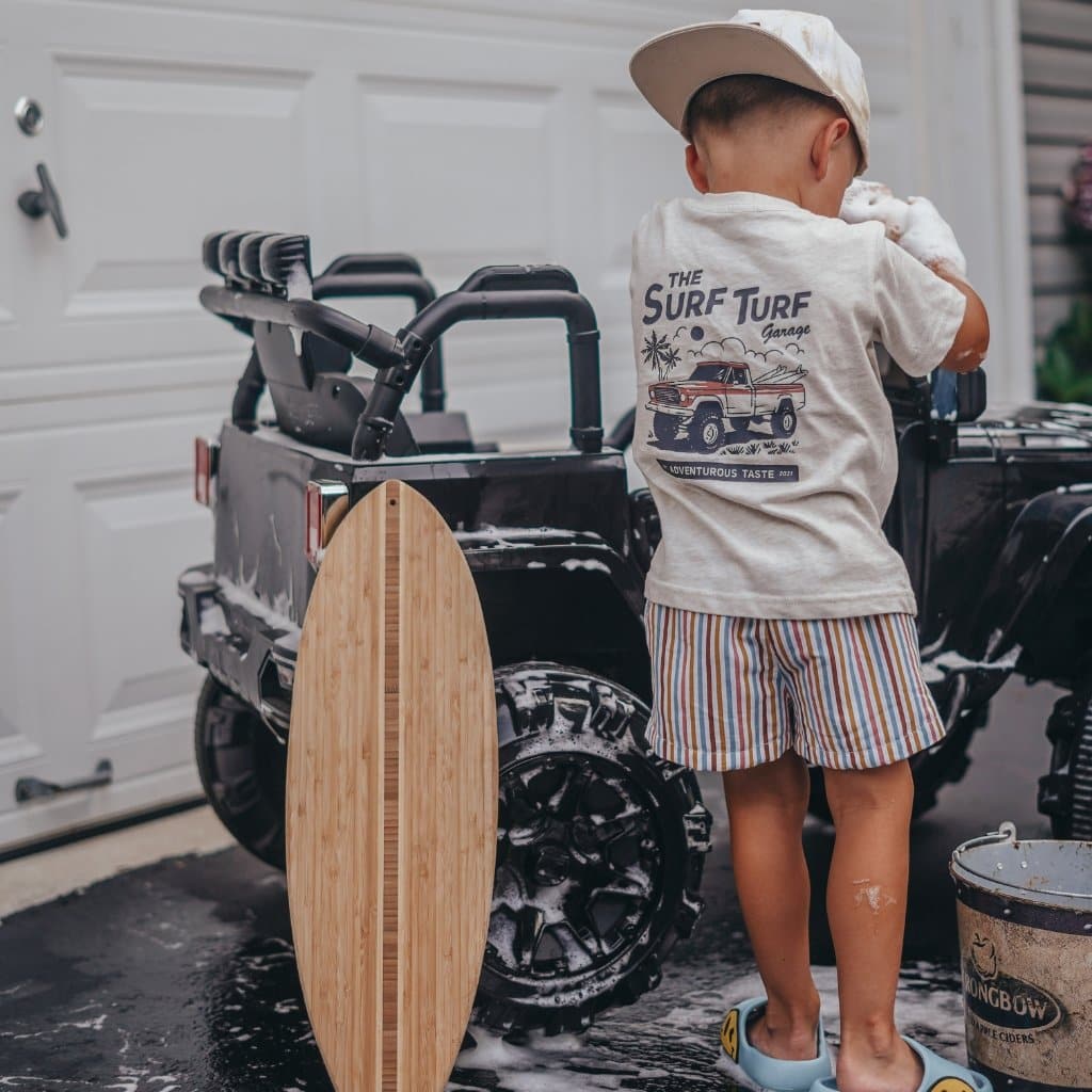 Young boy washing car, wearing Surf Turf Tee with skateboard detail