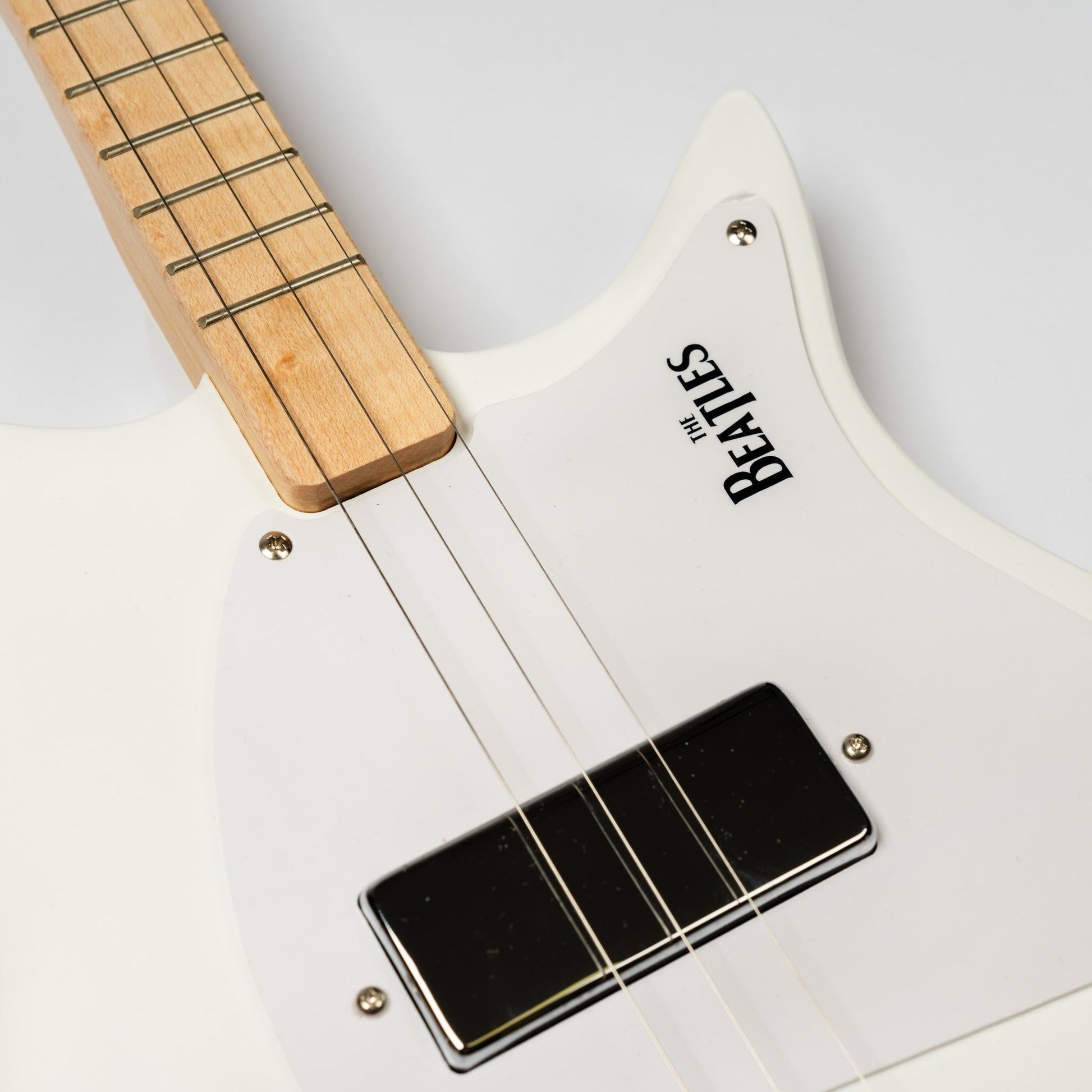 The white Beatles Loog guitar laying on its back.