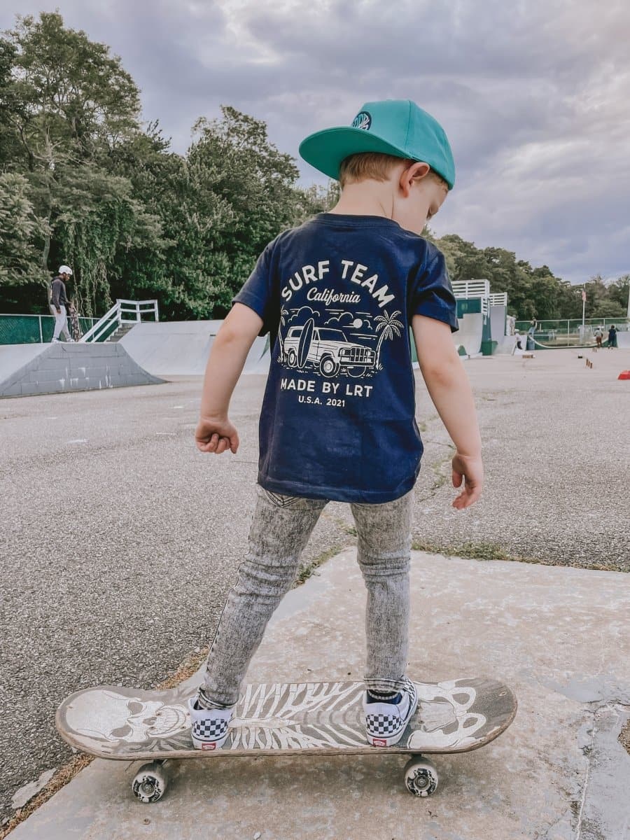 Child skateboarding in blue Surf Team tee and jeans.